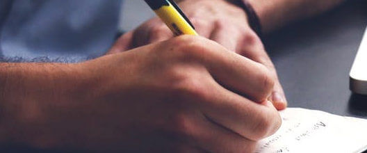 Closeup of a man writing on a piece of paper