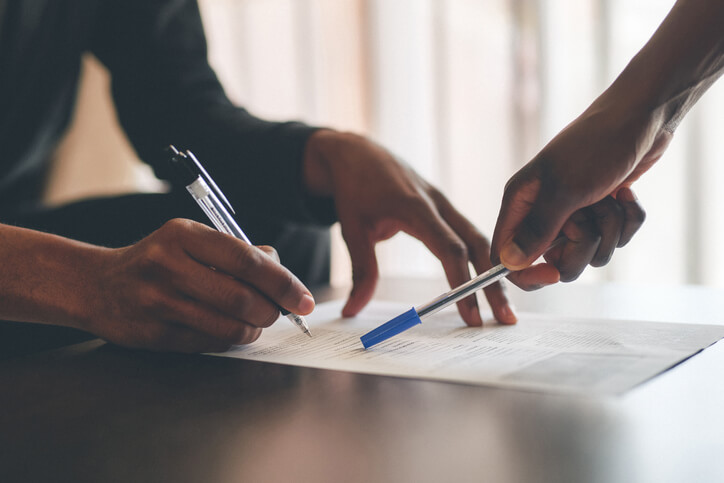 Two figures signing legal documents