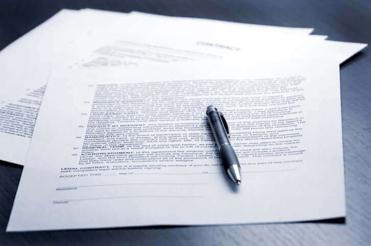 business contracts sitting on a table with a pen on top of them